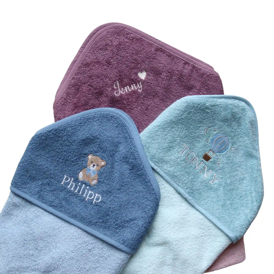 Kapuzenhandtuch mit Namen – gefaltete Badetücher in Blau, Türkis und Mauve